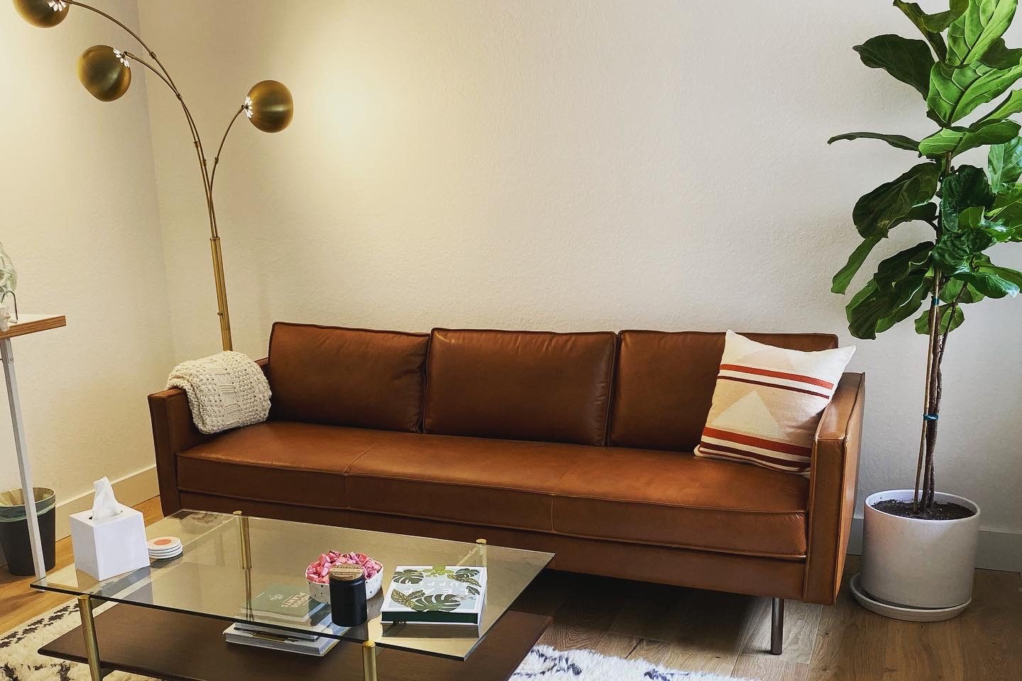 Warm Playa del Rey therapy office with a brown leather couch, plants, and a coffee table.